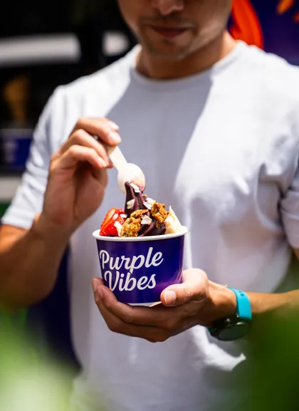 A customer eating an açaí bowl from a Purple Vibes cup