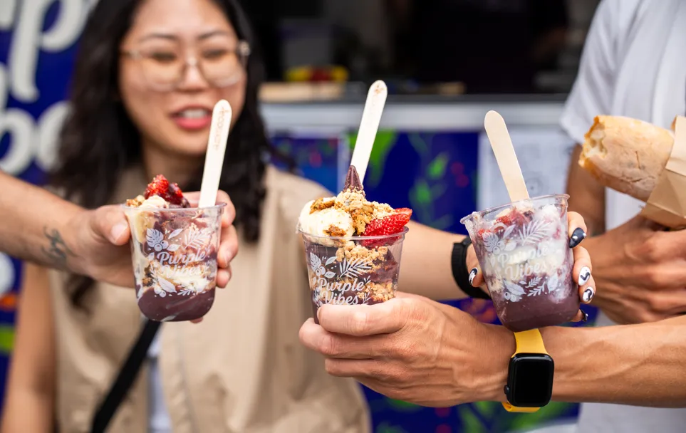 A group of customers holding Purple Vibes açaí cups at an event