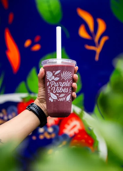 A Purple Vibes açaí smoothie held up in front of the trailer artwork