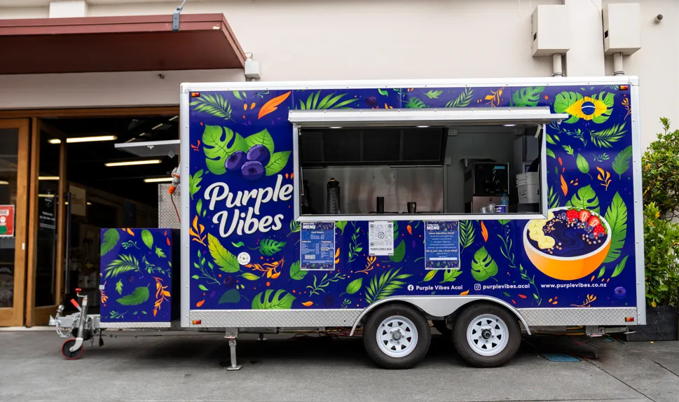 Purple Vibes food trailer, painted with tropical leaves and berries, parked in Auckland