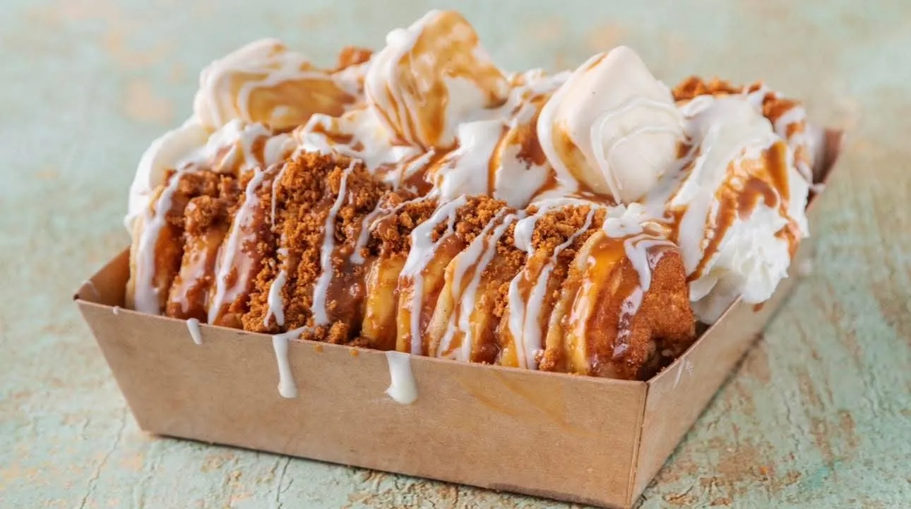 A tray of loaded churros topped with cream and caramel drizzle